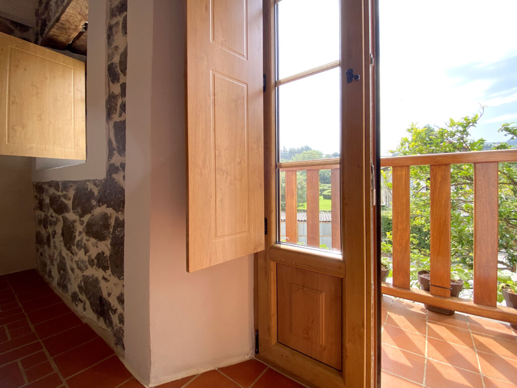 Puerta abierta hacia balcón con vista al jardín