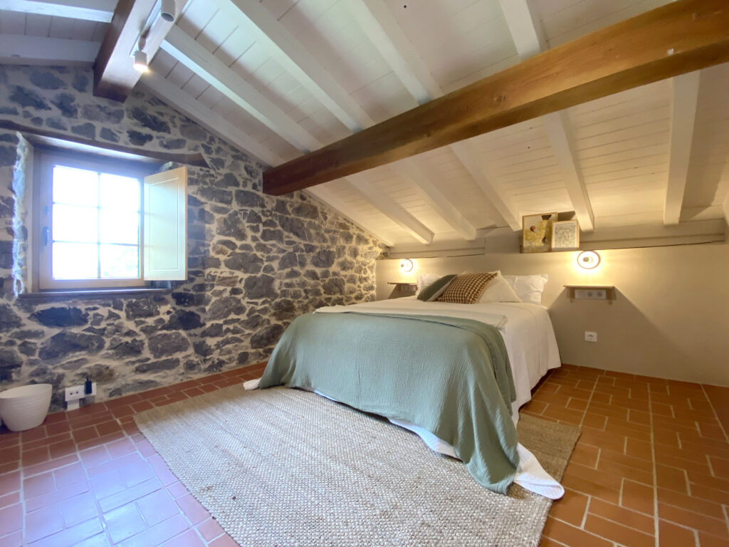 Habitación de piedra rústica con cama doble y ventana.
